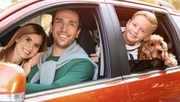 Ratgeber-Einreisebestimmungen_1200x527 Glückliche Familie mit Kind und Hund in einem orangefarbenen Auto auf einem sonnigen Ausflug