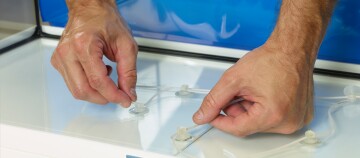 Hände befestigen Saugnäpfe mit transparentem Schlauch auf glatter Oberfläche in Werkstatt