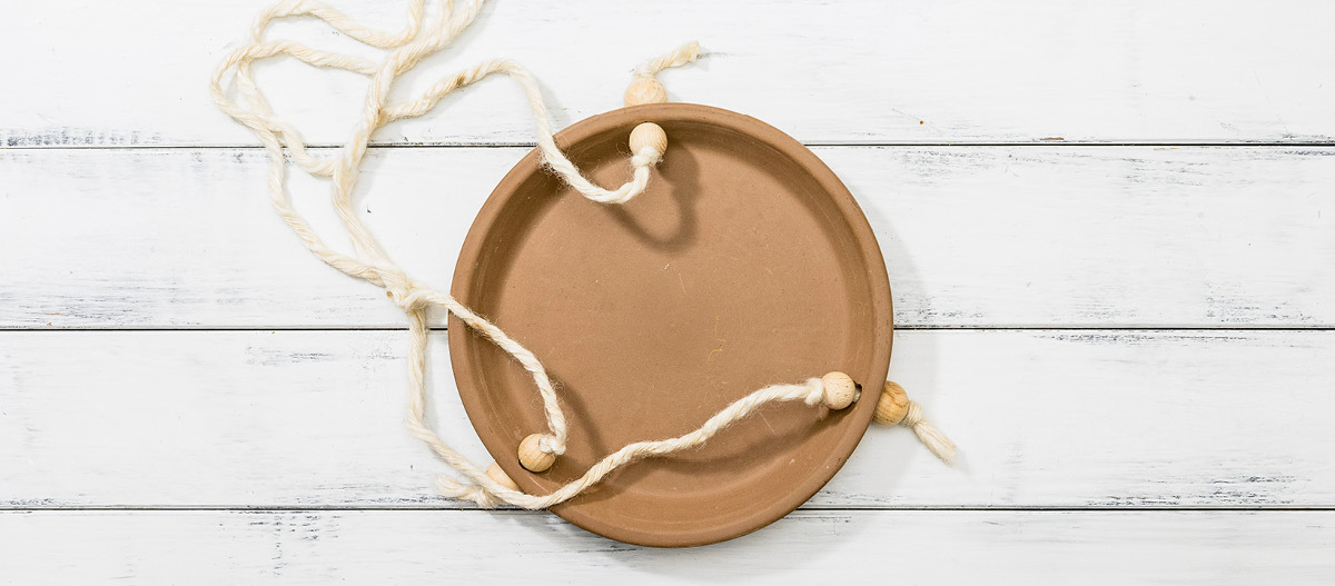 Schritt 3 Rundes hängendes Terrakotta-Pflanzentablett mit weißen Seilen und Holzperlen auf weißem Holzhintergrund