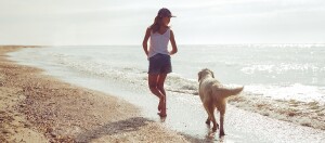 Mädchen läuft mit Hund am Strand