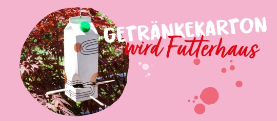 Kreatives Vogelhaus aus recyceltem Getränkekarton mit grüner Kappe und Holzstangen als Sitzstangen vor rotem Laub im Garten