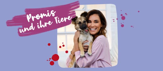 Glückliche Frau hält ihren kleinen Hund im Arm – Promis und ihre Tiere