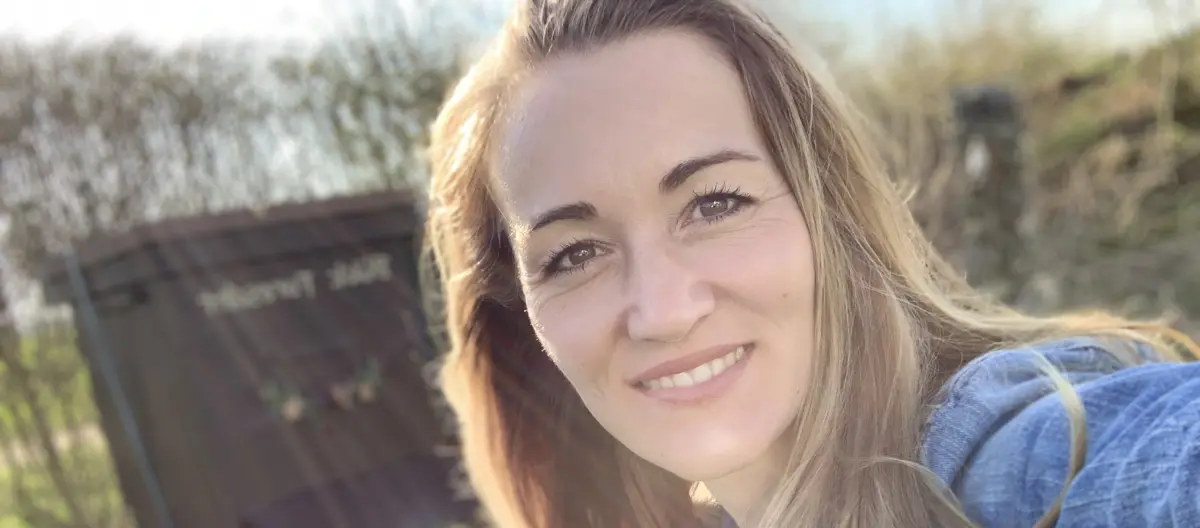 Nahaufnahme einer lächelnden Frau mit langen blonden Haaren im Freien bei Sonnenlicht