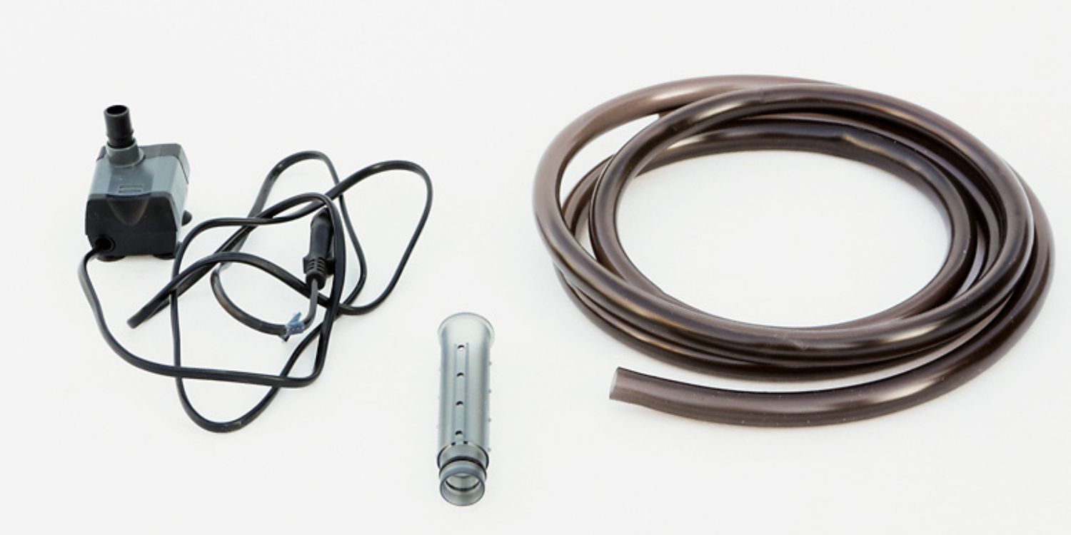 Vogeldusche2 Schwarze Wasserpumpe mit Kabel, transparenter Filteraufsatz und schwarzer flexibler Schlauch auf weißem Hintergrund