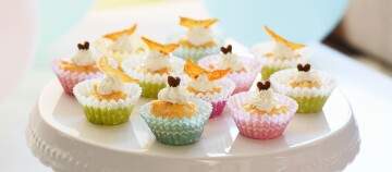 Kleine kleurrijke cupcakes met witte glazuur en decoratieve toppings op een witte taartstandaard