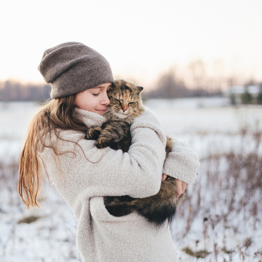 Eine Katze und ihre Halterin sind im Winter draußen