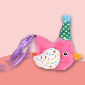 Buntes Plüschvogel-Spielzeug mit Partyhut, rosa Körper, weißem Flügel mit bunten Streuseln und lila Bändern als Schwanz
