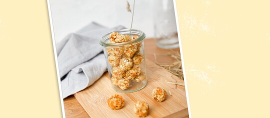 Glas mit hausgemachten Granola-Kugeln auf Holzbrett, natürliche Snacks mit Haferflocken und Trockenfrüchten