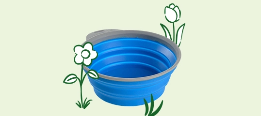 Bol pliable en silicone bleu avec bord gris, entouré de dessins de fleurs et d'herbe sur fond clair