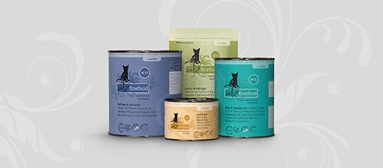 Vier Dosen Almo Nature Finefood Katzenfutter in verschiedenen Geschmacksrichtungen auf grauem Hintergrund.