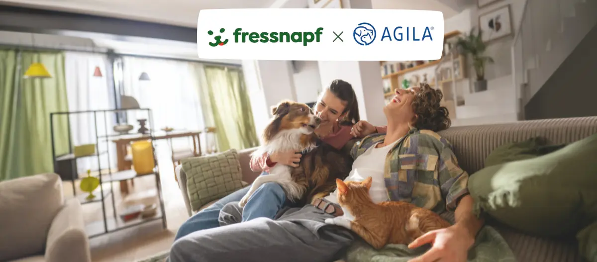 Glückliches Paar sitzt entspannt auf dem Sofa mit Hund und Katze in einem hellen Wohnzimmer; darüber das Logo „fressnapf × AGILA“