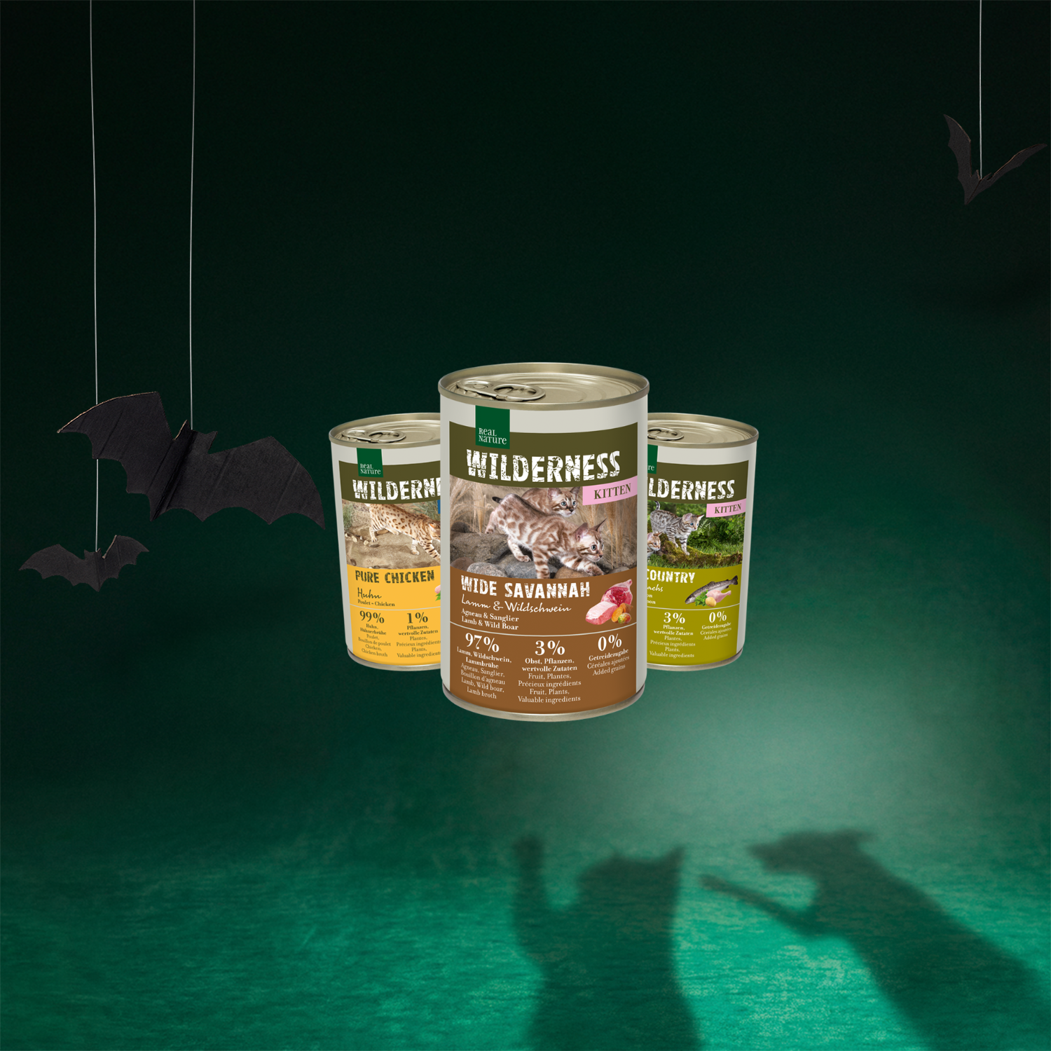 L'image représente trois boîtes de 400 g de nourriture humide pour chats des variétés Adult Pure Chicken, Kitten Wide Savannah et Kitten True Country de la marque REAL NATURE WILDERNESS.