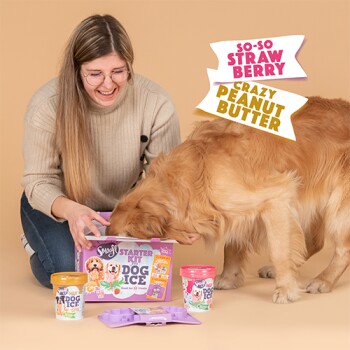 Kobieta i golden retriever bawią się kolorowym zestawem do lodów dla zwierząt, z smakami 'So-So Strawberry' i 'Crazy Peanut Butter.'