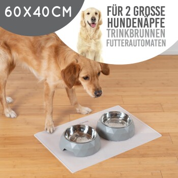 Ein Hund steht neben einer grauen Fütterungsmatte mit zwei großen, geometrischen Hundenäpfen. Der Text lautet '60X40CM für 2 große Hundenäpfe.'