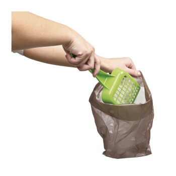 Eine Person verwendet eine grüne Katzentoilette-Schaufel, um Abfall in eine braune Plastiktüte zu entfernen, und demonstriert damit die Tierpflege.