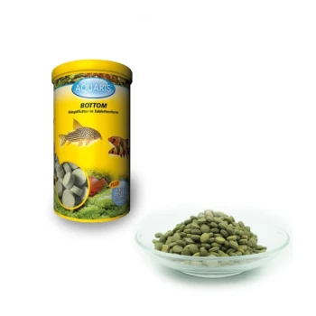 Aquaris Bottom Fischfutter in einem gelben Behälter, mit einem Teller grüner, tablettenförmiger Pellets daneben.