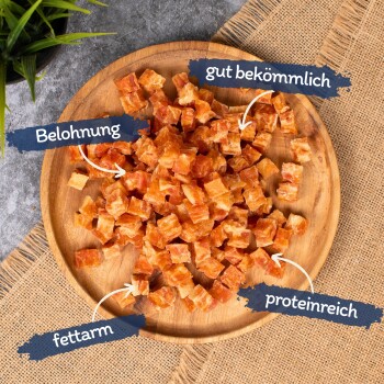 Ein Holzbrett mit orange-braunen Haustierleckereien, gekennzeichnet mit "Belohnung," "gut bekömlich," "fettarm," und "proteinreich."