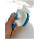 Eine Hand hält ein blau-weißes Haustierpflegewerkzeug mit einem strukturierten Griff und einem kammartigen Kopf, vor einem schlichten Hintergrund.