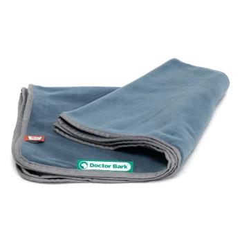 Eine gefaltete blaue Haustierdecke mit einem grauen Rand, mit einem grünen "Doctor Bark"-Logo und einem kleinen roten Etikett.