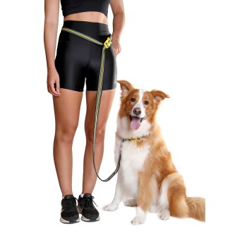 Eine Person in schwarzen Sportshorts und einem Crop-Top steht neben einem angeleinten Hund und zeigt eine stilvolle Haustierleine.