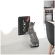 Eine graue Katze, die zu einem wandmontierten Kratzbrett greift, das 'LOVE' sagt, mit einem roten Anhänger, in einer modernen Küchenszene.
