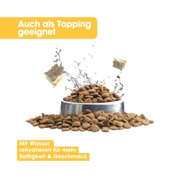 Eine Metallschüssel mit trockenem Tierfutter, mit Wasserflecken darüber. Text: "Auch als Topping geeignet" und "Mit Wasser rehydrieren für mehr Saftigkeit & Geschmack."
