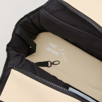 Innenansicht einer Haustiertragetasche mit schwarzem Innenfutter und beigem Äußeren, mit dem Text "HUND HIER PLATZIEREN" innen gedruckt.