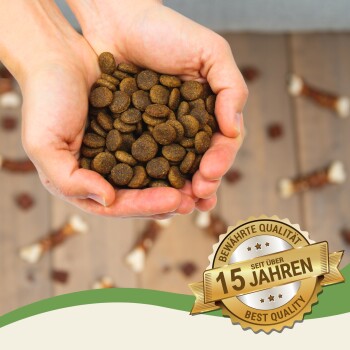 Ein Paar Hände hält einen Haufen brauner Haustierfutter-Kibble, mit einem Abzeichen, das "Bewährte Qualität seit über 15 Jahren" und "Best Quality" angibt.