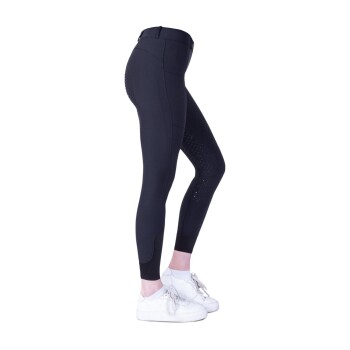 Seitenansicht einer Person, die schwarze Reitleggings mit hoher Taille und strukturierten Grip-Panels trägt, kombiniert mit weißen Turnschuhen.