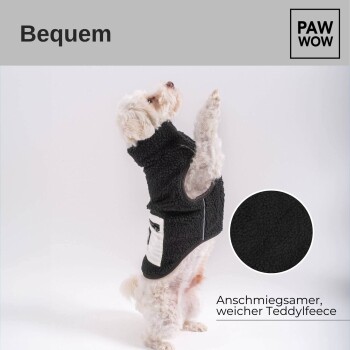 Ein kleiner weißer Hund in einer schwarzen Fleeceweste steht auf seinen Hinterbeinen, mit dem Text "Bequem" und "PAW WOW" darüber. Die Weste hat eine Tasche.