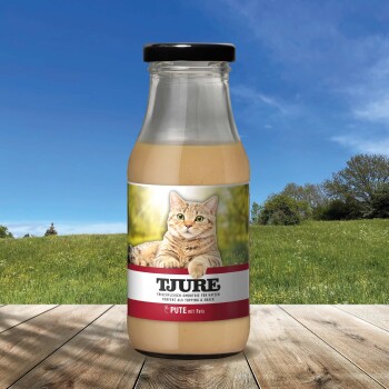Eine Flasche TJURE Katzen-Smoothie mit einer entspannten getigerten Katze auf dem Etikett, vor einem sonnigen Außenhintergrund.