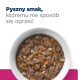 Biała miska wypełniona mokrą karmą dla zwierząt z kawałkami mięsa, marchewką i ziarnami, z napisem 'Pyszny smak, któremu nie sposób się oprzeć' powyżej.