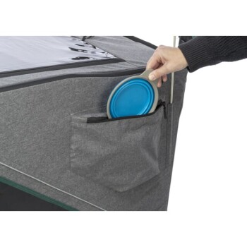 Eine Person holt einen blauen Hundescheibe aus einer Tasche an der Seite eines grauen Haustierzelt.