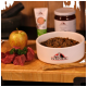 Weißer Napf mit Tacrenberg Hundefutter mit rohem Fleisch, Apfel und Petersilie auf einem Holzschneidebrett.