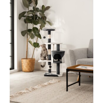 Eine getigerte Katze sitzt auf einem mehrstöckigen Katzenbaum mit grauem und weißem Stoff, mit einem Kratzbaum und einem gemütlichen Versteck, in einem modernen Wohnzimmer.