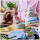 Eine Frau in einem rosa Shirt bietet einem braunen Hund einen runden Leckerbissen an, während sie eine hellblaue Schüssel mit ähnlichen Leckerbissen hält.