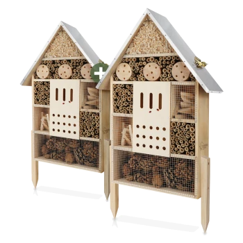 Zwei hölzerne Insektenhotels in Form von Häusern, die verschiedene Fächer mit natürlichen Materialien für nützliche Insekten enthalten.