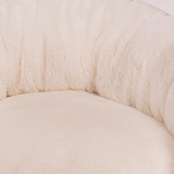 Ein plüschiges, cremefarbenes Haustierbett mit einer weichen, flauschigen Textur, in runder Form und mit erhöhten Rändern für Komfort.