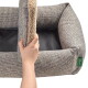 Hand hebt das herausnehmbare Fleece-Kissen in einem grauen Tweed-Haustierbett an; schwarzes Innenfutter sichtbar und grüner Anhänger mit der Aufschrift "HUNTER"
