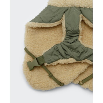 Olivfarbener gesteppter Hundemantel mit beiger Sherpa-Fütterung, verstellbaren elastischen Riemen und grüner Kunststoffschnalle.