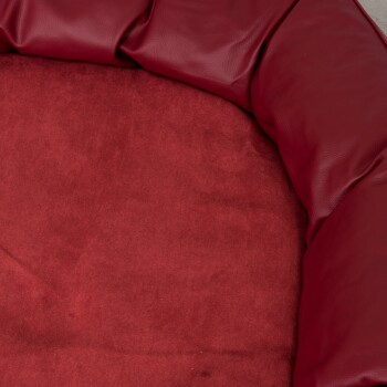 Schwarzes Haustierbett mit einer weichen, plüschigen Schlafoberfläche und einem abnehmbaren Kissen, mit einem lederähnlichen Äußeren und einem kleinen Logo-Patch.