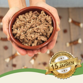 Eine Person hält eine braune Schüssel mit Hundefutter, umgeben von Hundeleckerlis, mit einem Abzeichen, das "Beste Qualität" und "15 Jahre" auf Deutsch angibt.