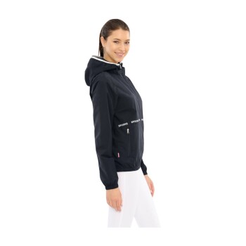 Eine Frau trägt eine schwarze Kapuzenjacke mit dem Aufdruck "SPOOKS" auf der Vorderseite, kombiniert mit weißen Hosen.