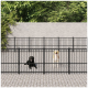 Zwei Hunde, ein schwarzer Labrador und ein gelber Labrador, stehen hinter einem schwarzen Metallzaun in einem Tiergehege, umgeben von Grün.