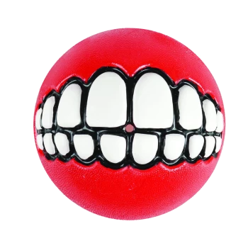 Balle jouet rouge pour chien avec un dessin cartoon d'un large sourire blanc et denté sur fond blanc.