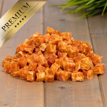 Ein Haufen kleiner, orange-brauner, gewürfelter Haustierleckereien auf einer Holzoberfläche, mit einem goldenen Banner "PREMIUM" in der oberen linken Ecke.