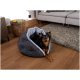 Ein kleiner schwarz-brauner Hund entspannt sich in einem gemütlichen, grauen Haustierbett in einem modernen Wohnzimmer mit Holzboden und einem plüschigen Teppich.