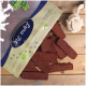 Eine Tüte "Premium Qualität" Haustierleckerlis kippt braune Leckerlis auf Holz, neben einem weißen Seilspielzeug.