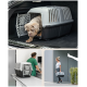 Eine hellgraue und schwarze Haustiertrage mit einem teilweise darin befindlichen Hund, die im Kofferraum eines Autos steht. Die Trage hat Belüftungsöffnungen und eine sichere Tür.