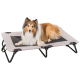 Ein flauschiger Collie, der auf einem erhöhten Hundebett mit einer grauen und schwarzen Stoffoberfläche ruht und Komfort und Stil zeigt.